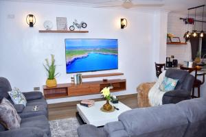 Zuri Luxe 2BR Beach apt.-Malindi في ماليندي: غرفة معيشة مع تلفزيون على الحائط