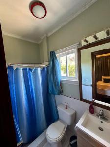 a bathroom with a toilet and a blue shower curtain at Casa Ejecutiva Boquete in Boquete