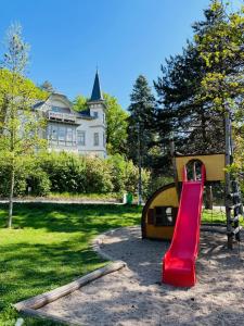 a playground with a red slide in front of a house at Ferienwohnung Villa Grützner in Freital