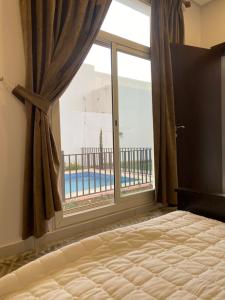 a bedroom with a window with a view of a pool at شاليه لونار in Unayzah