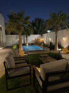 a patio with two chairs and a table and palm trees at شاليه لونار in Unayzah