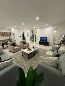 una gran sala de estar con sofás y TV. en شاليه لونار, en Unaizah