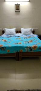 a bed with a blue comforter with flowers on it at Service Apartment Near Rameshwaram Cafe Brookefield in Bangalore