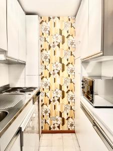 cocina con armarios blancos y papel pintado con motivos florales en Appartamento - Residence I Larici en Folgarida