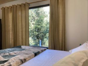 a bedroom with a bed and a large window at Sattal Valley Resort in Bhīm Tāl