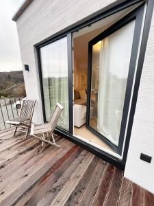 eine Terrasse mit 2 Stühlen und einem großen Fenster in der Unterkunft FeWo Anders - Neubau mit Balkon im Bergischen Land in Reichshof 