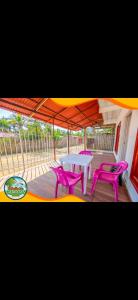 un patio con mesa y 2 sillas rosas en Cabaña hospedaje las Gaviotas en Moñitos