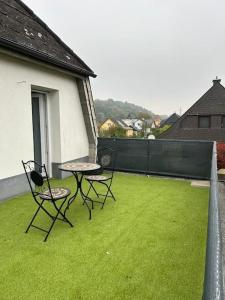 2 Stühle und ein Tisch auf einer Terrasse mit Gras in der Unterkunft Schönes Haus in Sankt Pölten