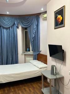 Habitación pequeña con cama y TV. en Manand Hotel, en Ereván