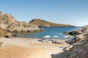 a beach with umbrellas and chairs and the water at Beachfront Studio Kyma East ~ Crete's Hidden Gem in Kali Limenes