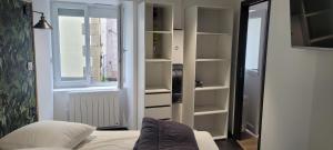 ein Schlafzimmer mit einem Bett, einem Fenster und Regalen in der Unterkunft Maison de Jérôme et Cynthia in Lannéanou