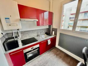 a small kitchen with red cabinets and a window at Le Lovely avec parking in Amiens