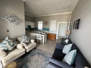 a living room with two couches and a kitchen at Unit 8 Alwil Ocean View Villa in Struisbaai