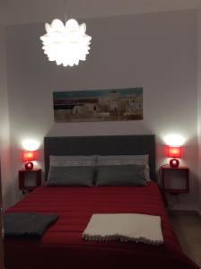 ピアッツァ・アルメリーナにあるApartment Sant Andreaのベッドルーム1室(赤いベッド1台、赤いランプ2つ付)
