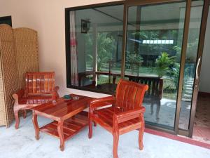 ランタ島にあるバーン ロング ビーチの椅子2脚、木製テーブル、テーブル、ガラス窓が備わる客室です。