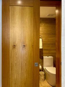 a bathroom with a toilet and a wooden door at Casa Coral in San Felipe de Puerto Plata
