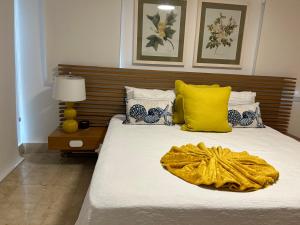 a bedroom with a bed with a yellow blanket on it at Casa Coral in San Felipe de Puerto Plata