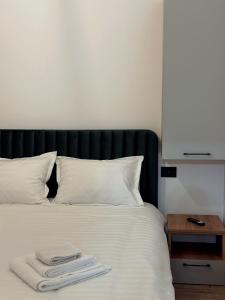 a bed with white sheets and a black headboard and a table at North Kaban in Borşa