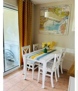 una mesa de comedor blanca con sillas y un mapa en la pared en Rdj aux issambres, en La Garonnette-Plage