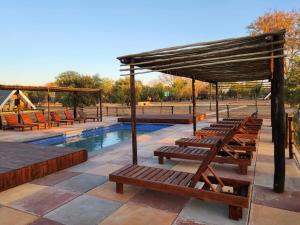 a row of wooden benches next to a swimming pool at Mzimkhulu Ranch & Resort in Dinokeng Game Reserve