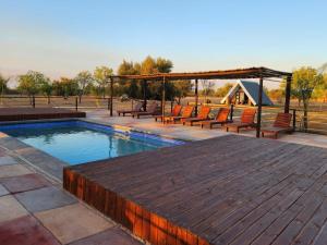 a swimming pool with benches and a wooden deck at Mzimkhulu Ranch & Resort in Dinokeng Game Reserve