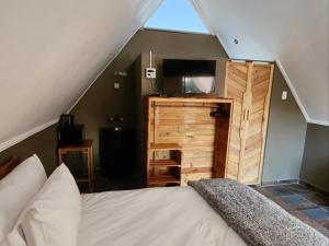 ein Schlafzimmer mit einem Bett und einem TV im Dachgeschoss in der Unterkunft Mzimkhulu Ranch & Resort in Dinokeng Game Reserve