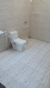 a bathroom with a toilet in a white tiled floor at The Meraki Beach Resort in Gokarna