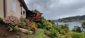 dom na wzgórzu z kwiatami obok rzeki w obiekcie Habitación con vista al mar w mieście Puerto Montt