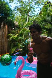 Ein Mann steht neben einem rosa Flamingo-Drink in der Unterkunft Maui Hostels Tulum in Tulum