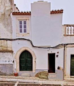 a white building with green doors and a window at A Casa do Castelo in Estremoz