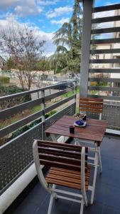 una mesa de madera y un banco en un balcón en Appartement de standing au centre de Chassieu en Chassieu