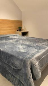 Un dormitorio con una cama con una manta gris. en Loft do Vale en Pomerode
