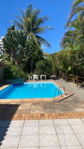 a swimming pool with two chairs and palm trees at Lindo Vilage em Praia do Flamengo! in Salvador