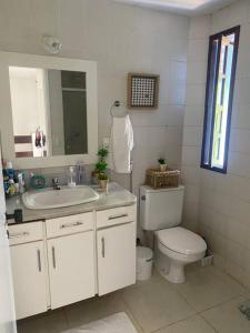 a bathroom with a sink and a toilet and a mirror at Lindo Vilage em Praia do Flamengo! in Salvador