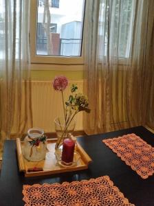 een tafel met een dienblad met een vaas met bloemen en een kaars bij Virginia Apartment in Thessaloniki