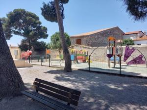 un parque con un banco junto a un parque infantil en Agréable maison de village au calme en Sigean