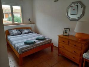 ein Schlafzimmer mit einem Bett, einer Kommode und einem Fenster in der Unterkunft Agréable maison de village au calme in Sigean