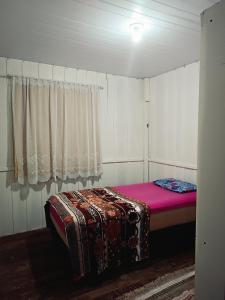 a bedroom with a bed in a room with a window at Casa Temporada in Imbituba