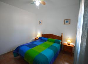 a bedroom with a green and blue bed with two lamps at Chiclana.Balconera.1ªlínea playa in Chiclana de la Frontera