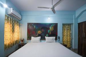 um quarto com uma cama grande e uma pintura na parede em OYO Blue Cherry Guest House em Ballygunge