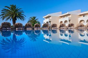 a swimming pool in front of a hotel with palm trees at Argile Resort & Spa in Lixouri