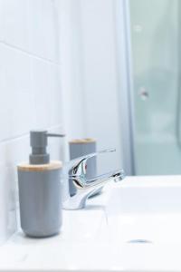 a bathroom sink with a faucet and two cups at Grand T1 bis calme et confortable 2 in Castres +5 photos
