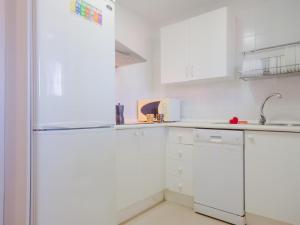 uma cozinha branca com armários brancos e um frigorífico em Chiclana.Balconera.1ªlínea playa em Chiclana de la Frontera