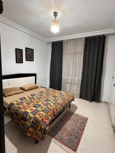 a bedroom with a bed with a colorful blanket at Appartement L'aouina cité wahat in Tunis