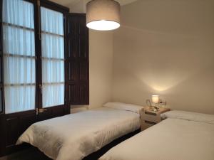 two beds in a room with two windows at Granada Historic Center Apartment in Granada