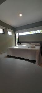 a bedroom with a large white bed with windows at Acacias Mina Clavero in Mina Clavero