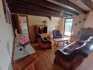 sala de estar con muebles de cuero y mesa en Le Refuge, en Opont