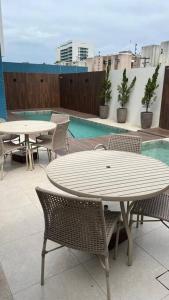 a patio with tables and chairs and a pool at Studio a 300m da praia in Maceió