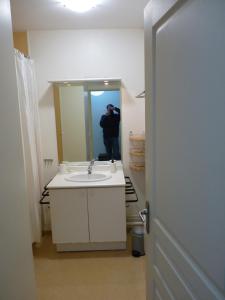 Ein Mann fotografiert ein Badezimmer mit Waschbecken. in der Unterkunft Le Caldarium - Classé 2 Etoiles - Thermes 10 mn - 6 pers in Avène + 11 Fotos