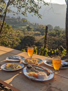 a table with plates of food and glasses of orange juice at Mamaterra Glamping in Macanal